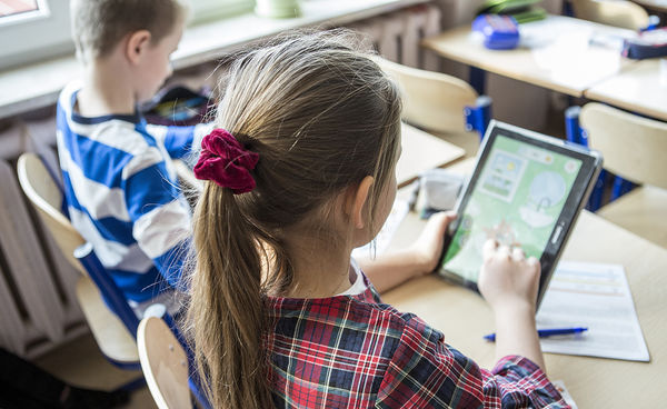 Dziewczynka przed ekranem tableta siedząca obok chłopca