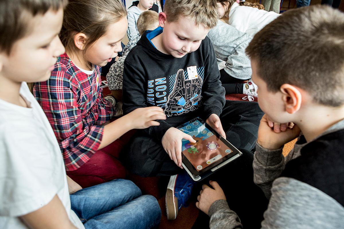 Dzieci siedzące w kółku przed ekranem tableta