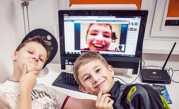 Zdjęcie dwóch chłopców odwróconych tyłem do ekranu komputera