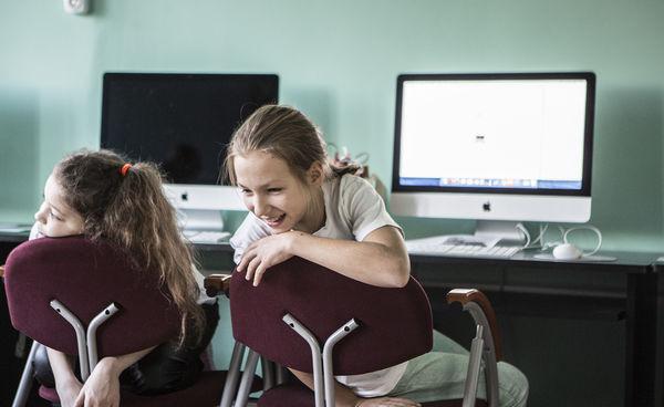 Dwie dziewczynki odwrócone tyłem do ekranów komputerów