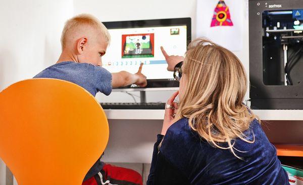 Kobieta pokazująca coś dziecku na ekranie komputera
