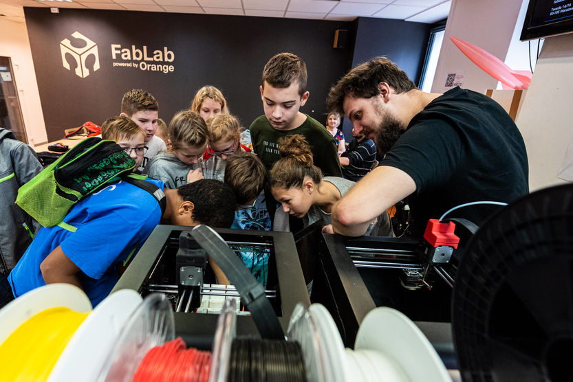 Grupa osób patrząca na drukarkę 3D